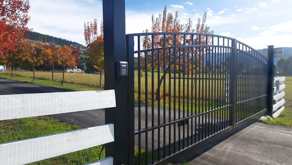 Black ornamental wrought-iron driveway gate installed at residential property — gate installation service
